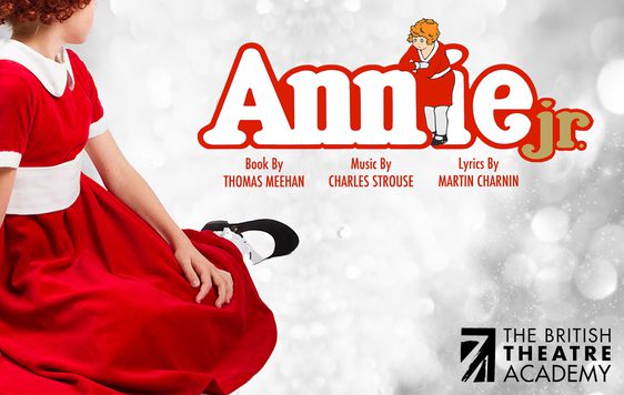A young girl is sitting in a red dress facing away next to the show title, "Annie Jr." with the British Theatre Academy logo in the bottom corner.
