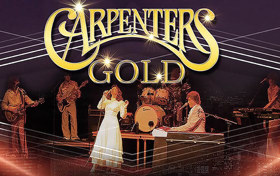 A band performing on stage as "The Carpenters" with light beams surrounding them. The show title "Carpenters Gold" is shown at the top of the image