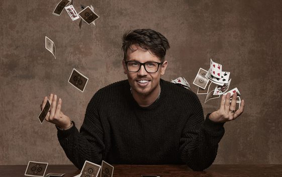 James Phelan, smiling into the camera while flicking playing cards into the air