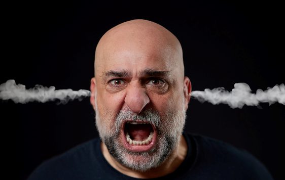 Comedian Omid Djalili is yelling with steam coming out of his ears against a black background