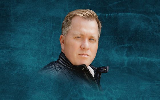 Tony Stockwell, wearing a leather jacket, is shown against a dark blue background