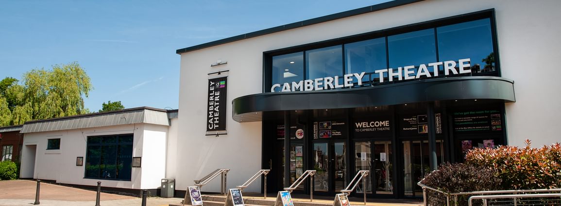 The front of Camberley Theatre, a white rendered building with steps and ramp up to the front doors.