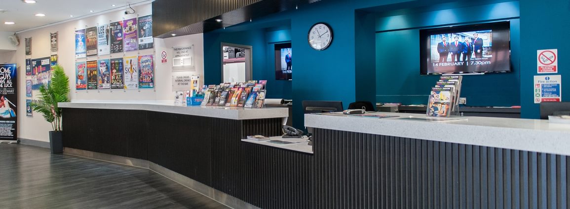 The Box Office counter at Camberley Theatre with leaflets on the counter and posters on the wall