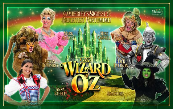 The show title "the Wizard of Oz" written in gold set against a green sparkling background showing a yellow brick road and a green castle. Characters are shown on either side.