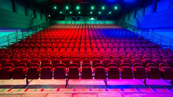 A front facing view of all of the red seats at Camberley Theatre lit up green, red and blue